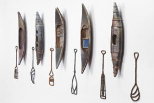 Five canoes of different material hung on a wall