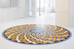A spiral geometric floor design in a white hallway