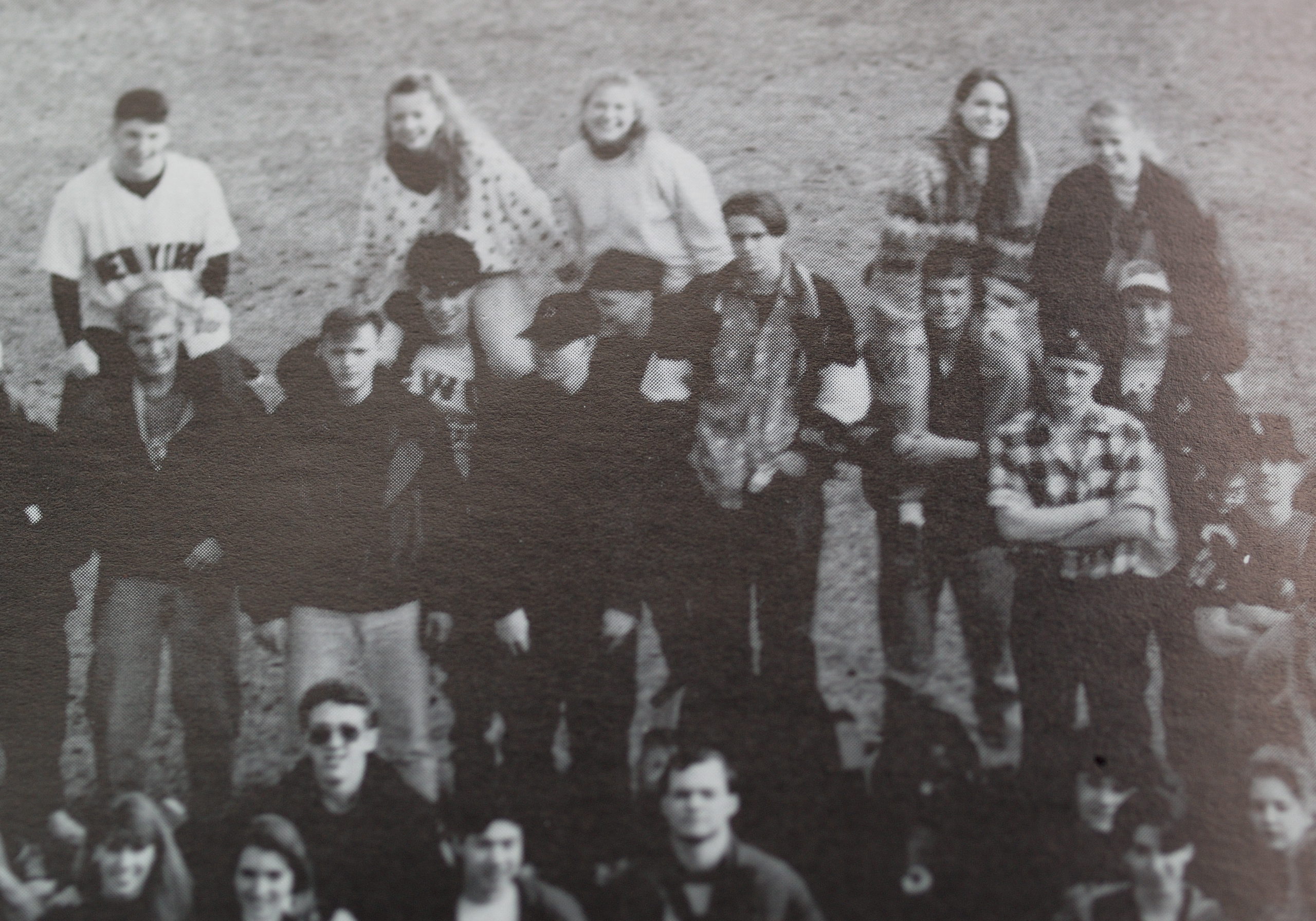 Old image of a group of highschool kids standing around, some of the girls on boy's shoulders.