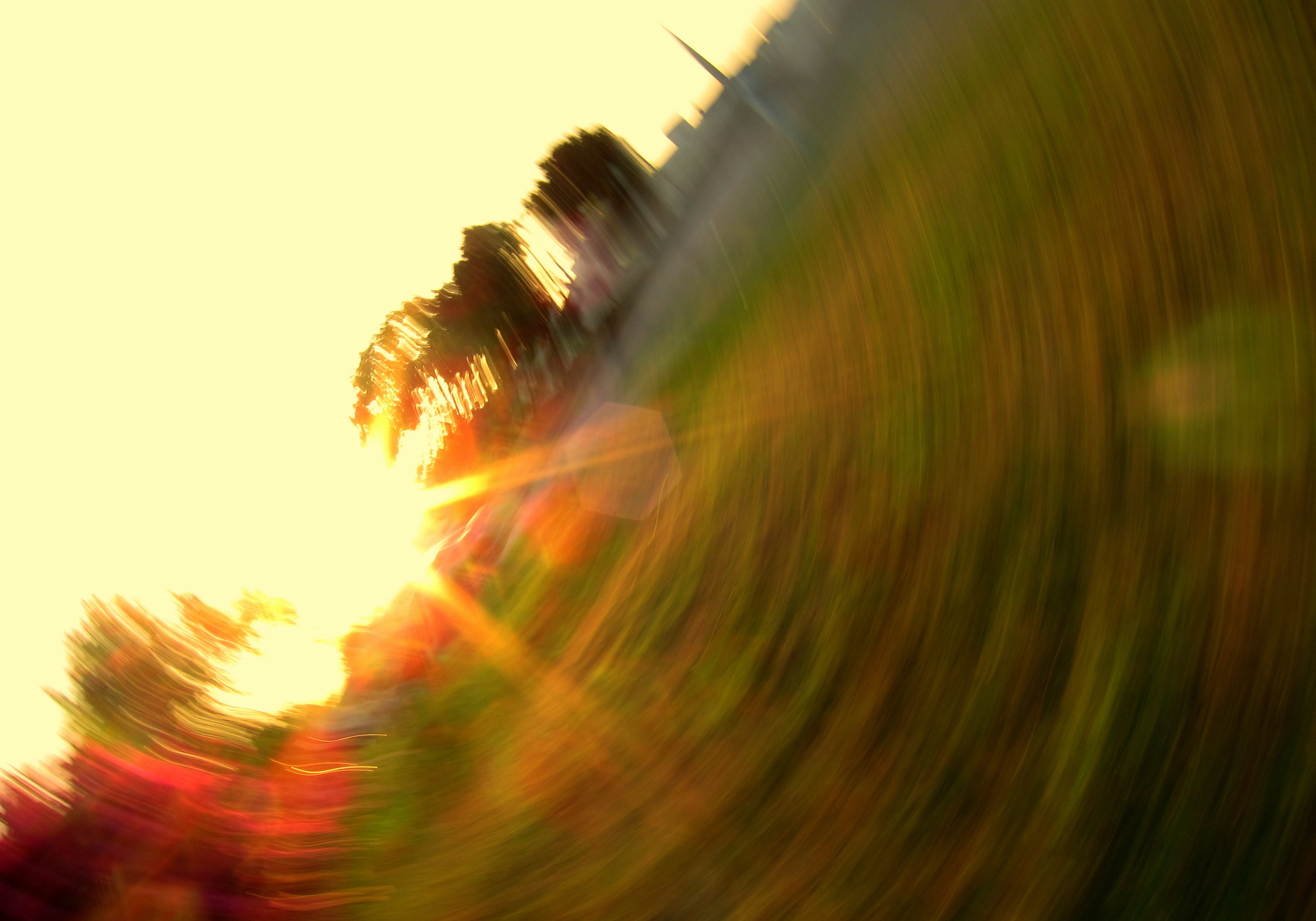 image of a field and a yellow sky and a burst of sunlight in a blurry, motion-fraught circle from a spinning camera.